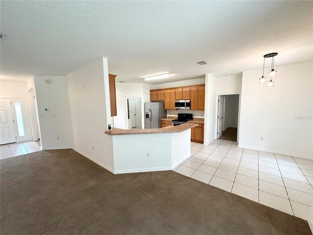 15 Ruth Dr, Palm Coast, FL 32164 - kitchen featuring stainless steel appliances, light tile patterned floors, baseboards, brown cabinets, and a peninsula