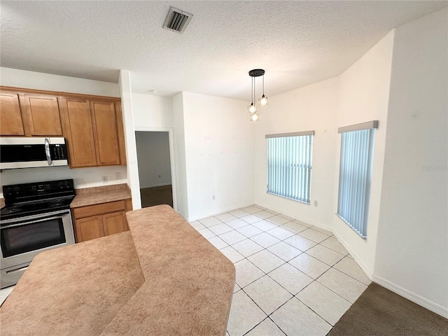 15 Ruth Dr, Palm Coast, FL 32164 - kitchen featuring appliances with stainless steel finishes, light tile patterned floors, hanging light fixtures, brown cabinetry, and baseboards