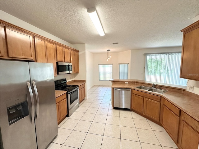 15 Ruth Dr, Palm Coast, FL 32164 - kitchen with stainless steel appliances, a sink, brown cabinetry, light tile patterned floors, and a textured ceiling