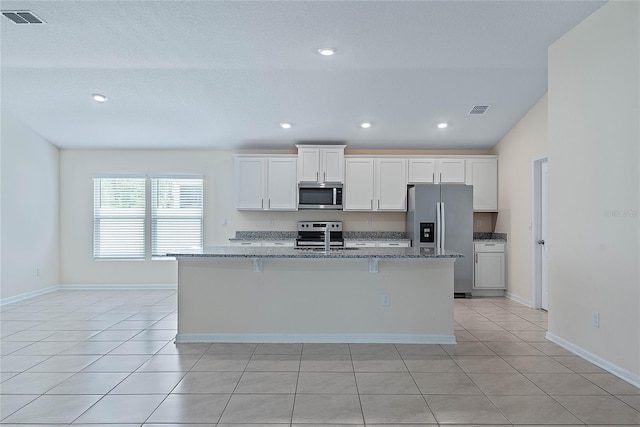 25 Red Top Ln, Palm Coast, FL 32164 - kitchen featuring appliances with stainless steel finishes, a center island with sink, white cabinetry, stone counters, and recessed lighting
