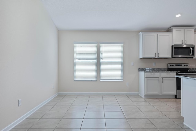 25 Red Top Ln, Palm Coast, FL 32164 - kitchen with stainless steel appliances, white cabinets, light stone countertops, light tile patterned floors, and recessed lighting