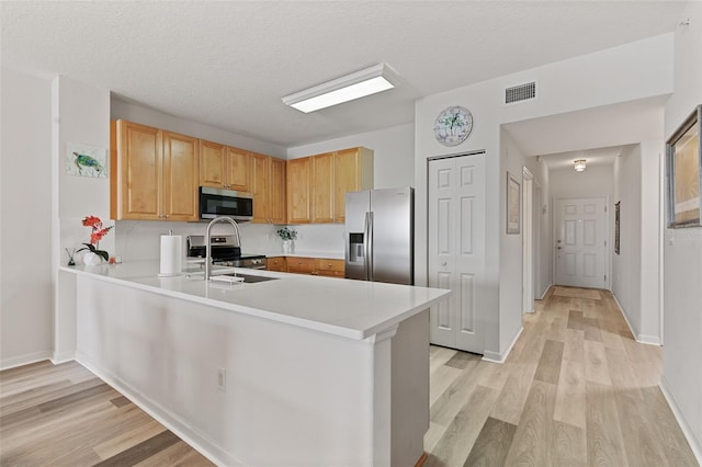 80 Surfview Dr Unit 718, Palm Coast, FL 32137 - kitchen featuring appliances with stainless steel finishes, light wood-style flooring, a peninsula, light countertops, and a textured ceiling