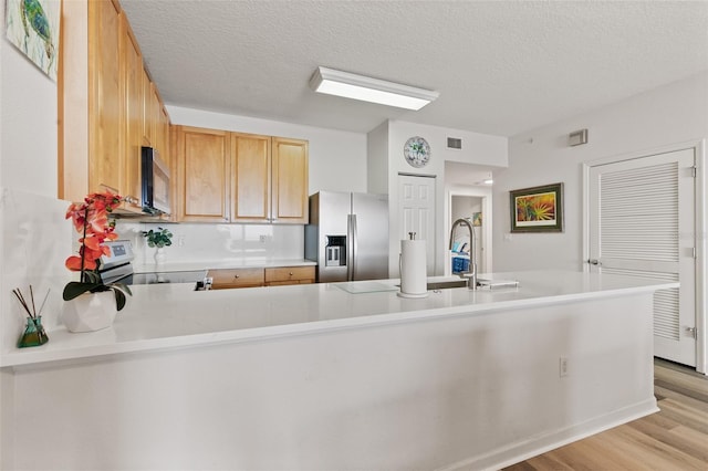 80 Surfview Dr Unit 718, Palm Coast, FL 32137 - kitchen with stainless steel appliances, light countertops, light wood-style flooring, a textured ceiling, and a peninsula