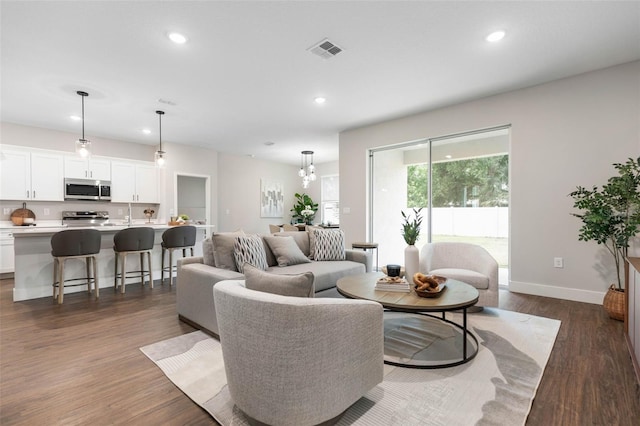 living area with recessed lighting, dark wood-type flooring, and baseboards