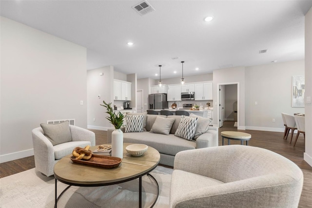 living area with baseboards, wood finished floors, and recessed lighting