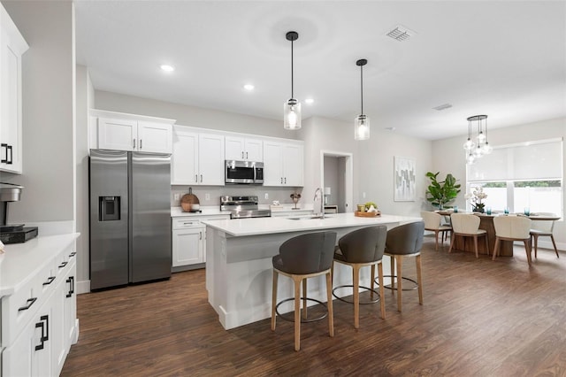 kitchen featuring stainless steel appliances, light countertops, a breakfast bar area, dark wood finished floors, and recessed lighting