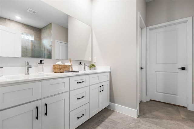 bathroom featuring a shower stall, double vanity, and baseboards