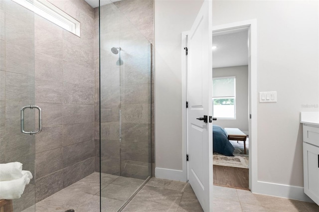 bathroom with a stall shower, ensuite bathroom, vanity, baseboards, and tile patterned flooring