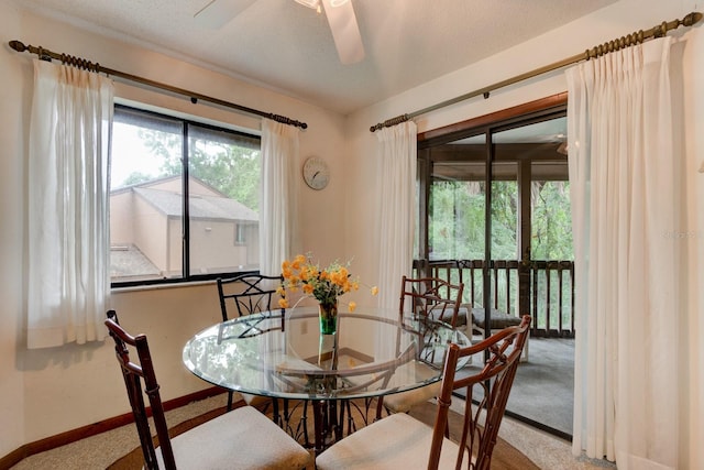 carpeted dining room featuring ceiling fan and baseboards