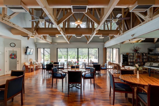 dining area featuring a ceiling fan, a towering ceiling, and wood finished floors
