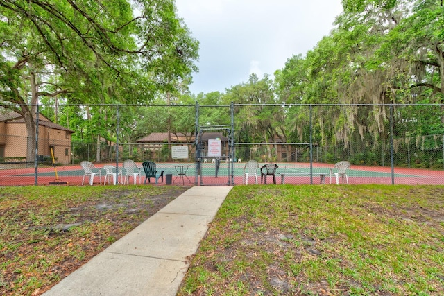 view of community featuring fence, a tennis court, and a gate