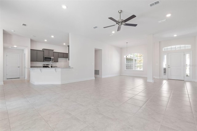 unfurnished living room with recessed lighting, ceiling fan, light tile patterned flooring, baseboards, and a chandelier
