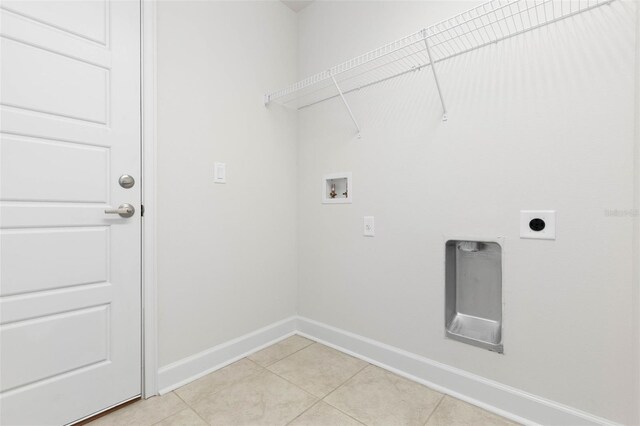 washroom with washer hookup, electric dryer hookup, light tile patterned flooring, and baseboards