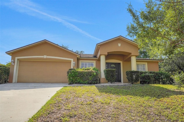 view of front of property with stucco siding, a garage, driveway, and a front lawn