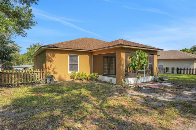 rear view of property featuring french doors, stucco siding, and a sunroom