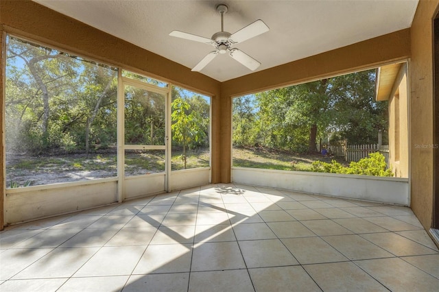 unfurnished sunroom featuring a ceiling fan and plenty of natural light