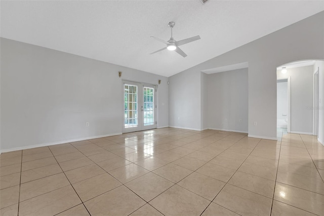 empty room with light tile patterned flooring, lofted ceiling, arched walkways, ceiling fan, and baseboards