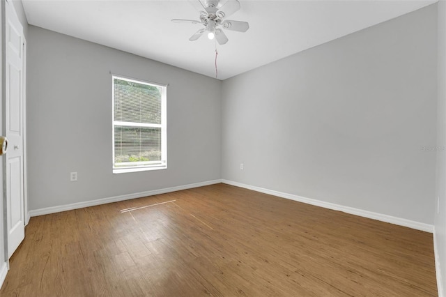 empty room with ceiling fan, wood finished floors, and baseboards