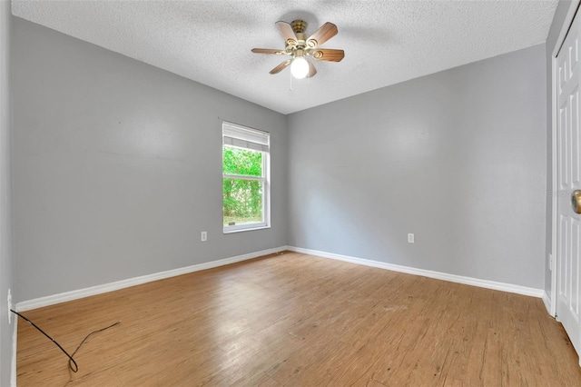 unfurnished room with a textured ceiling, wood finished floors, baseboards, and a ceiling fan