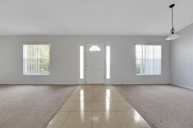 entrance foyer with carpet flooring, baseboards, and tile patterned flooring
