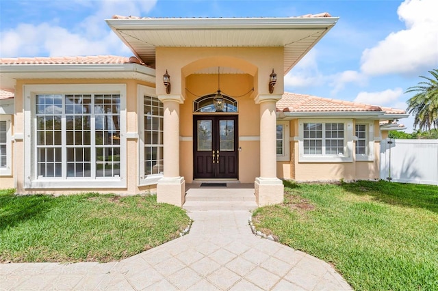 property entrance with stucco siding, french doors, and a tiled roof