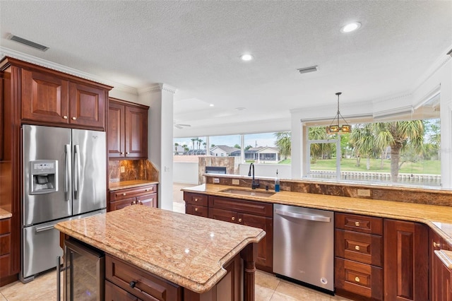 kitchen featuring appliances with stainless steel finishes, a sink, beverage cooler, light stone counters, and a kitchen island