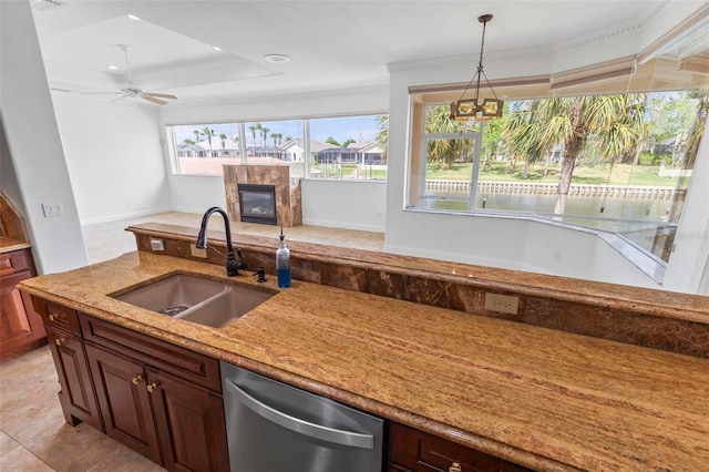 kitchen featuring a sink, stainless steel dishwasher, light stone countertops, decorative light fixtures, and a high end fireplace