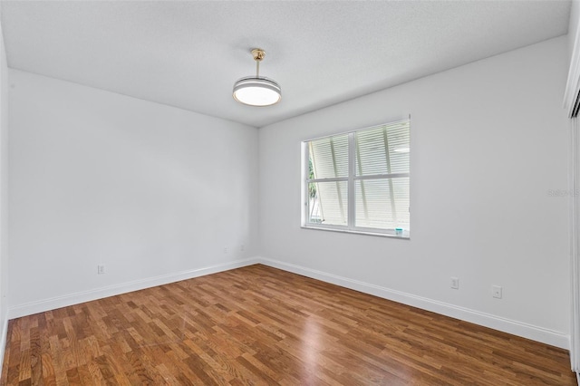 spare room featuring wood finished floors and baseboards