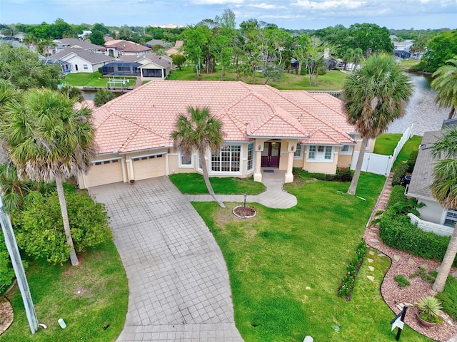 mediterranean / spanish home with a tiled roof, an attached garage, decorative driveway, and a residential view