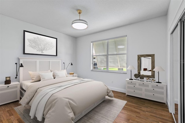 bedroom with wood finished floors, baseboards, and a closet