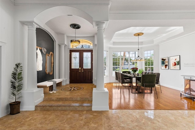 foyer featuring decorative columns, a chandelier, arched walkways, baseboards, and crown molding