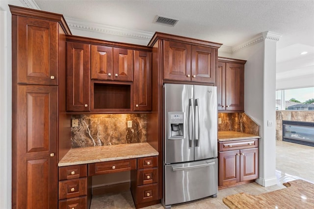 kitchen featuring stainless steel refrigerator with ice dispenser, backsplash, light stone counters, ornamental molding, and a textured ceiling