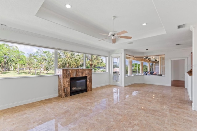unfurnished living room with a raised ceiling, a ceiling fan, a tile fireplace, baseboards, and recessed lighting