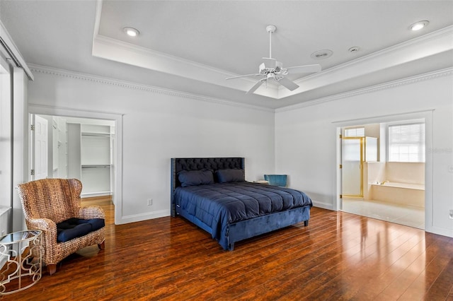 bedroom with ornamental molding, a tray ceiling, hardwood / wood-style floors, a spacious closet, and a closet