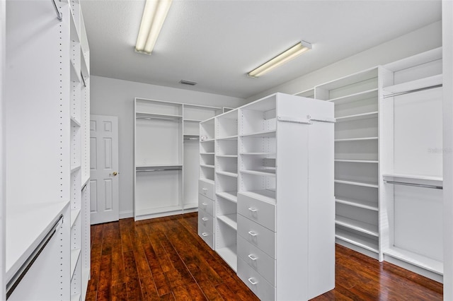 walk in closet with dark wood-style floors