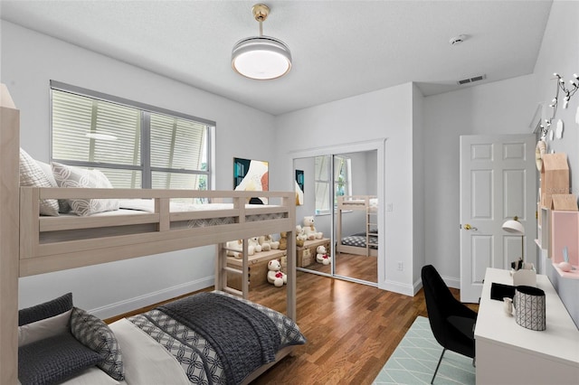 bedroom featuring baseboards, wood finished floors, and a closet