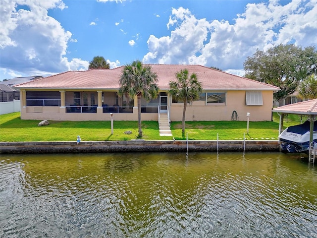back of house featuring a water view, a tiled roof, stucco siding, and a yard