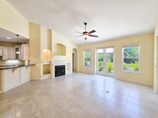 71 N Riverwalk Dr, Palm Coast, FL 32137 - unfurnished living room featuring a ceiling fan, a fireplace, light tile patterned floors, baseboards, and a textured ceiling