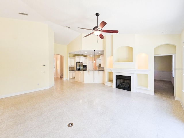 71 N Riverwalk Dr, Palm Coast, FL 32137 - unfurnished living room with a ceiling fan, a fireplace, light tile patterned floors, baseboards, and arched walkways