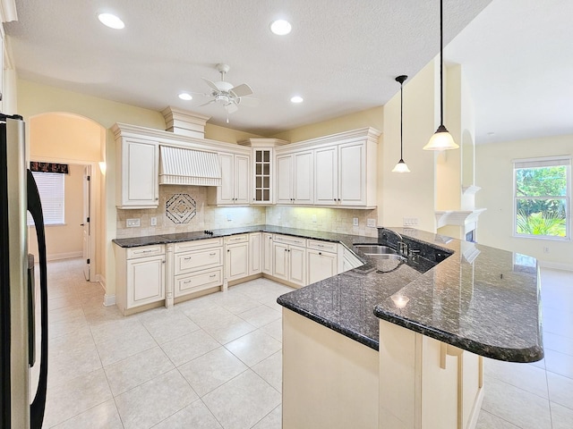 71 N Riverwalk Dr, Palm Coast, FL 32137 - kitchen with freestanding refrigerator, custom range hood, a sink, a peninsula, and a ceiling fan