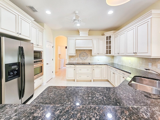 71 N Riverwalk Dr, Palm Coast, FL 32137 - kitchen with stainless steel appliances, a ceiling fan, a sink, decorative backsplash, and dark stone countertops