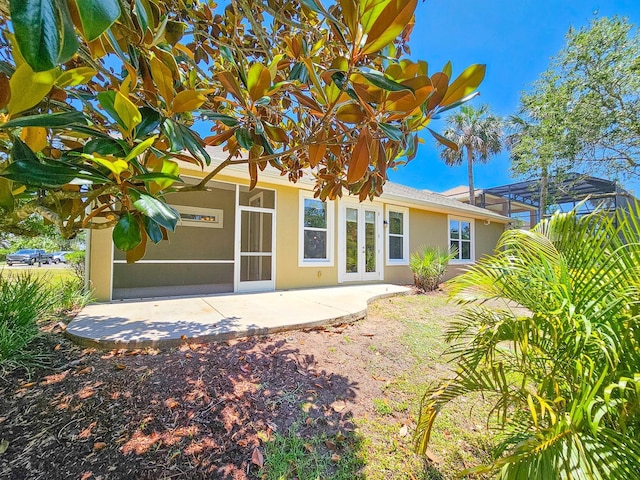 71 N Riverwalk Dr, Palm Coast, FL 32137 - back of house with french doors, a patio area, stucco siding, and glass enclosure