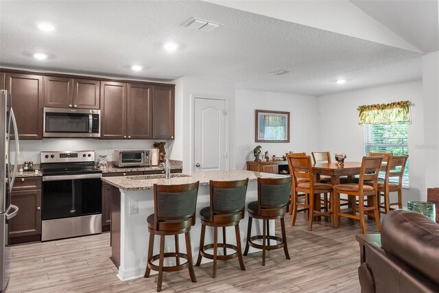9 Waldron Pl, Palm Coast, FL 32164 - kitchen with appliances with stainless steel finishes, light wood-type flooring, a kitchen island with sink, a kitchen bar, and recessed lighting