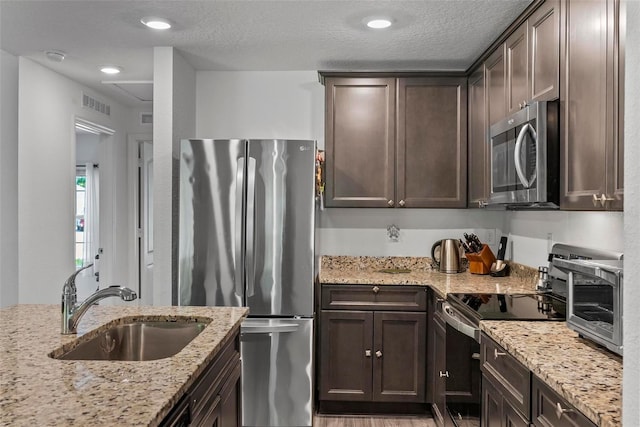 9 Waldron Pl, Palm Coast, FL 32164 - kitchen featuring stainless steel appliances, a sink, dark brown cabinetry, light stone counters, and a textured ceiling