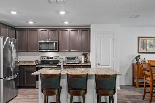 9 Waldron Pl, Palm Coast, FL 32164 - kitchen featuring stainless steel appliances, dark brown cabinets, light wood-style floors, recessed lighting, and a textured ceiling