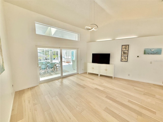 4 Cotton Ct, Palm Coast, FL 32137 - unfurnished living room featuring light wood-style floors, a towering ceiling, and baseboards