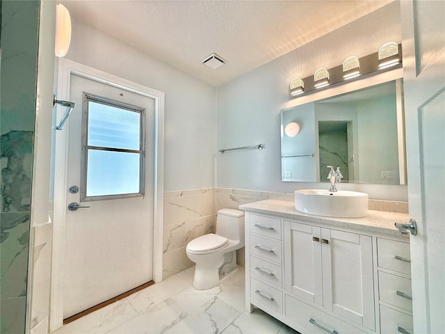 4 Cotton Ct, Palm Coast, FL 32137 - bathroom with marble look tile flooring, toilet, tile walls, vanity, and a wainscoted wall