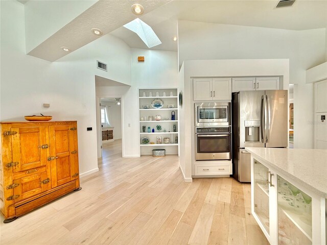 4 Cotton Ct, Palm Coast, FL 32137 - kitchen featuring stainless steel appliances, a skylight, high vaulted ceiling, light wood-type flooring, and light stone countertops