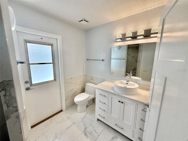 4 Cotton Ct, Palm Coast, FL 32137 - bathroom featuring marble look tile flooring, toilet, vanity, a marble finish shower, and a wainscoted wall