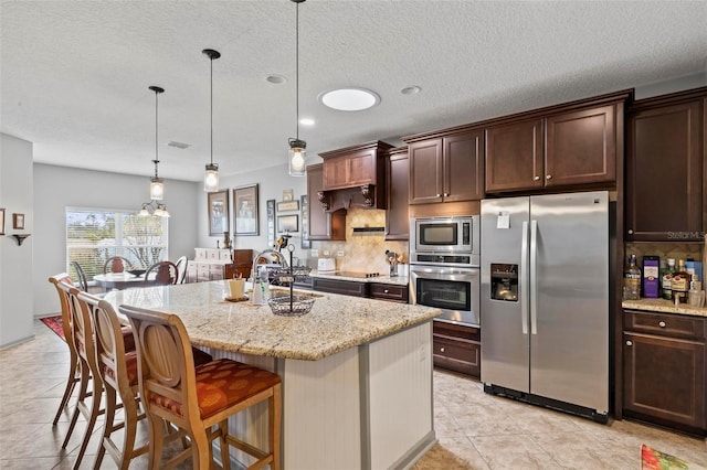 123 N Starling Dr, Palm Coast, FL 32164 - kitchen featuring appliances with stainless steel finishes, a breakfast bar area, dark brown cabinetry, decorative backsplash, and light stone counters